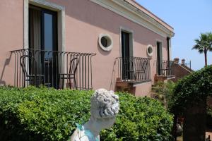 a statue in front of a pink building at IL Ciliegio Dell 'Etna in Giarre