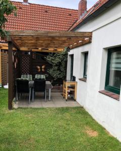 a patio with a table and chairs under a wooden pergola at Großer Hookie in Hooksiel