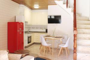 Una cocina con un refrigerador rojo y una mesa con sillas blancas. en La casita de Triana, en Cambados 40 fotos más
