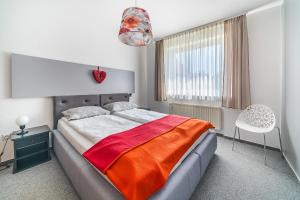 a bedroom with a bed with an orange blanket on it at Willa Onyks Apartamenty in Jastrzębia Góra