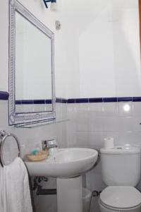 a bathroom with a sink and a toilet and a mirror at Hostal El Espinel in Zahara de los Atunes