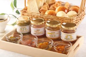 a tray with jars of jam and bread and a basket of bread at Hotel Quest Shimizu in Shizuoka