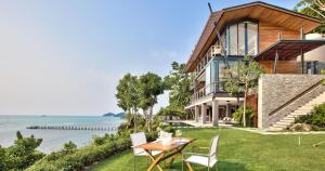 een huis met een tafel en stoelen aan de oceaan bij The View in Taling Ngam Beach