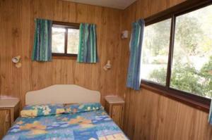 a bedroom with a bed and two windows at Tuross Lakeside Holiday Park in Tuross Heads