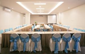 idoop Hotel Lombok في ماتارام: قاعة اجتماعات كبيرة مع طاولة طويلة مع بعرصي زرقاء