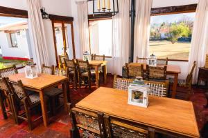 a restaurant with wooden tables and chairs and windows at ESTANCIA LOS CUARTOS in Tafí del Valle