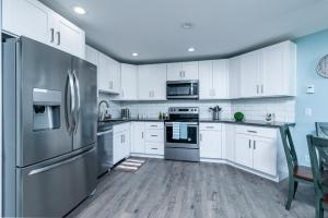 a kitchen with white cabinets and stainless steel appliances at Birch Bay waterfront condo - Lofted layout & steps from beach in Blaine