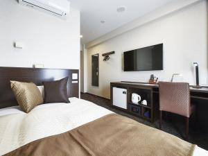 a bedroom with a bed and a desk with a television at The Celecton Omiya Kaisoku Kitamoto Ekimae in Kitamoto