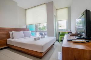 a bedroom with a bed and a desk with a computer at LeGreen Suite Tebet in Jakarta