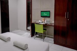 a hotel room with a bed and a desk with a computer at LeGreen Suite Setiabudi in Jakarta
