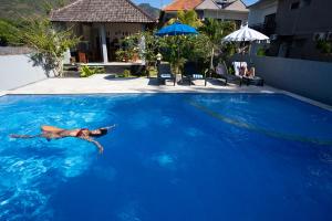 un homme nage dans une grande piscine bleue dans l'établissement Bali Dive Resort Amed, à Amed