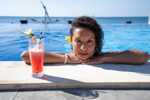 a woman in a swimming pool with a drink at Bali Dive Resort Amed in Amed