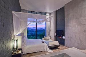 a bedroom with a bed and a large window at Sala Khaoyai in Wangkata