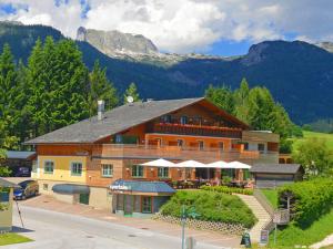 a large wooden building with mountains in the background at Der Seebacherhof in Tauplitz