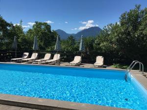 a swimming pool with chairs and mountains in the background at Residence Bichler in Merano