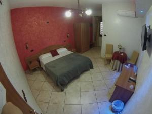 ノーラにあるHotel Il Giardino degli Aranciの赤い壁のベッドルーム1室(ベッド1台付)