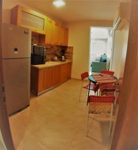een keuken met een koelkast en een tafel en stoelen bij Charming beach 2 room flat in Haifa