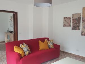 un sofá rojo con almohadas amarillas en la sala de estar. en Appartamento la Canvetta, en Santa Maria Maggiore