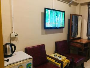 a living room with two chairs and a tv on the wall at Nett Hotel in Lop Buri