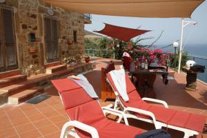 a patio with red chairs and a table with a view at Camere & Case Vacanze Lo Scoglio in Castel di Tusa