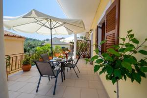 un patio con mesa, sillas y sombrilla en Voula Apartments en Gaios