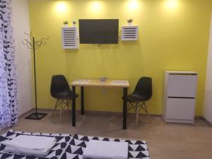 Habitación con mesa, 2 sillas y TV. en Dandelo, en Novi Sad