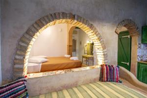 Un dormitorio con un arco y una cama. en Elpiniki en Alinda
