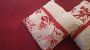 Una almohada roja y blanca con flores. en Hôtel Les Deux Magots, en La Roche-Bernard