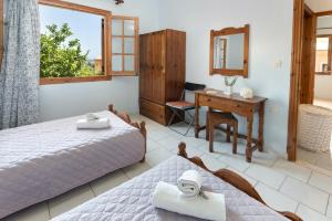 a bedroom with two beds and a desk and a mirror at Voula Apartments in Gaios