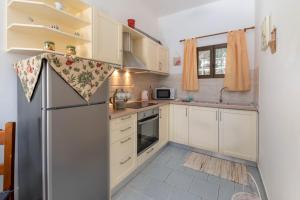 a kitchen with white cabinets and a refrigerator at Voula Apartments in Gaios