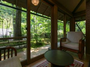 eine abgeschirmte Veranda mit einem Tisch und einem Stuhl in der Unterkunft Kurokawa-So in Minamioguni