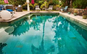 una piscina de agua azul en un patio en La Villa de la Plage en La Saline les Bains