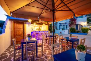 een restaurant met tafels en stoelen en een parasol bij Elpiniki in Alinda