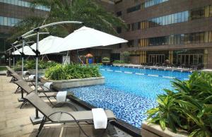 een zwembad met stoelen en een parasol naast een gebouw bij Yunkai Hotel in Guangzhou