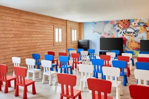 Habitación con TV y sillas rojas blancas y azules. en Jaz Maraya Resort en Coraya Bay