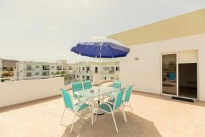 a table with chairs and an umbrella on a balcony at Oceania Bay Village in Pyla