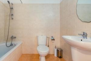 a bathroom with a toilet and a sink and a bath tub at Oceania Bay Village in Pyla