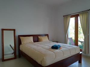 a bedroom with a bed with a blue hat on it at Lala Homestay Bingin in Uluwatu