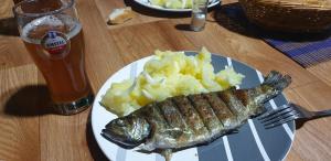 a plate of food with a fish and mashed potatoes and a beer at Auto Kamp Lav in Kulen Vakuf