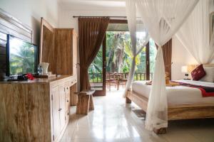 a bedroom with a bed and a television in a room at Alam Terrace Cottages in Ubud