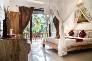 a bedroom with a bed with curtains and a television at Alam Terrace Cottages in Ubud