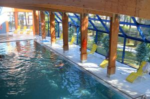 a swimming pool with yellow chairs in a building at Ośrodek Wypoczynku i Rekreacji Venus in Mrzeżyno