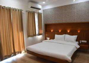 een slaapkamer met een groot wit bed in een kamer bij Hotel President Banquet & Lawn in Aurangabad