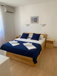 a bedroom with a large bed with blue sheets and towels at Kos Apartments in Bol