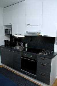 a kitchen with white cabinets and a black stove top oven at Kotimaailma Apartments Joensuu - Koulukatu 21 in Joensuu