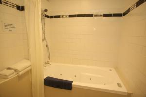 bagno bianco con vasca e doccia di The Grand Hotel Wanganui a Whanganui