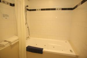 a white bathroom with a tub and a shower at The Grand Hotel Wanganui in Whanganui