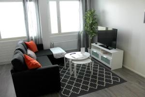 a living room with a black couch and a tv at Kotimaailma Apartments Joensuu - Koskikatu 11 in Joensuu