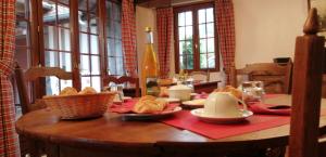 una mesa con pan y una botella de vino y ventanas en Aux Trois Damoiselles en Beuvron-en-Auge