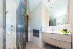 La salle de bains est pourvue d'un lavabo et d'une douche. dans l'établissement ArtiHome, à Hopfgarten im Brixental